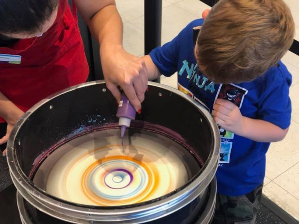 Artist helping a young boy doing spin art