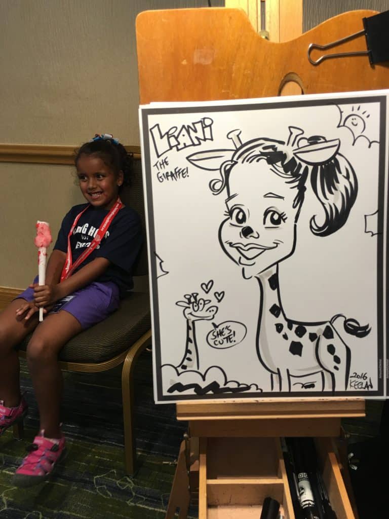 girl having her caricature drawn as a giraffe