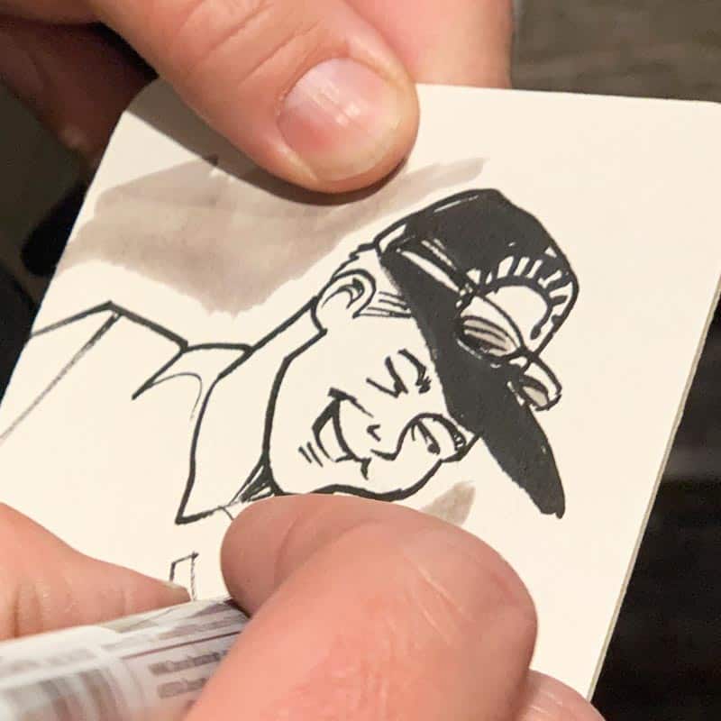 artist drawing a face on a coaster