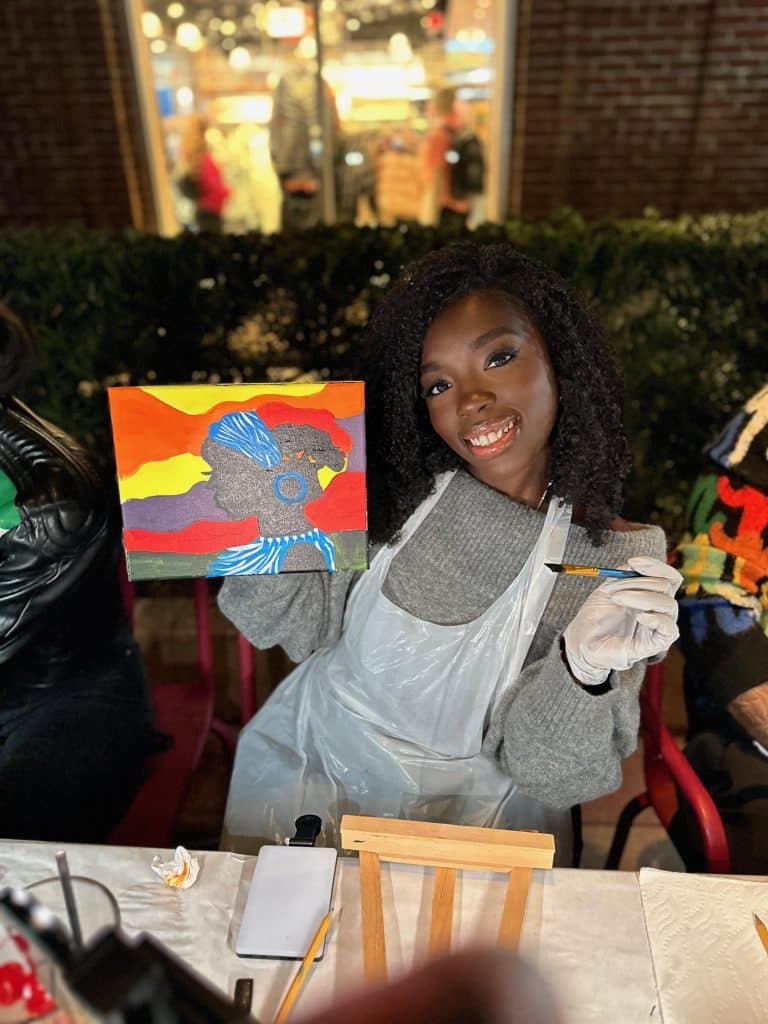 woman posing with canvas painting she's doing