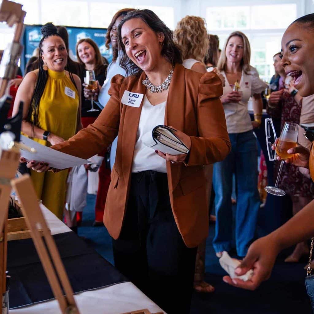 woman looking excited at piece of artwork at a corporate event