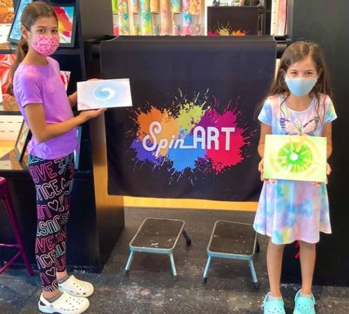 two kids showing off their spin art pieces
